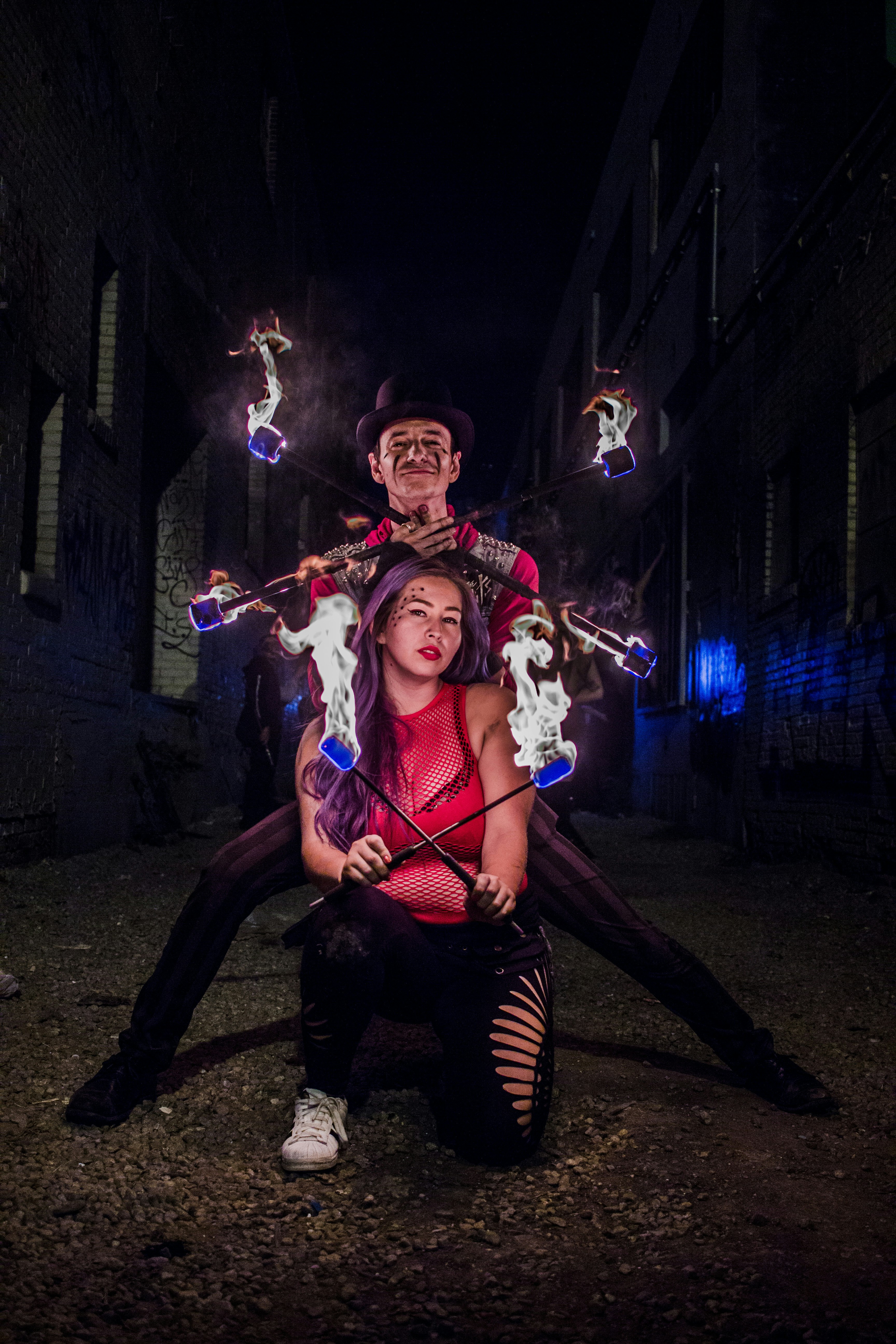 woman and man holding stick with fire during night time